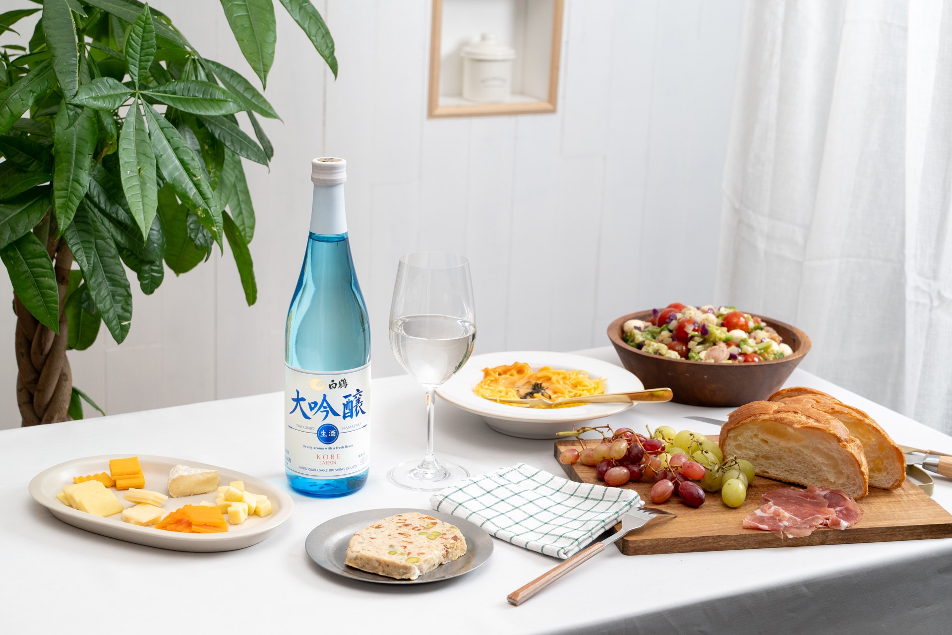 白鶴の日本酒と料理を白いテーブルに配置した撮影。器やグリーンを組み合わせた食卓のスタイリング